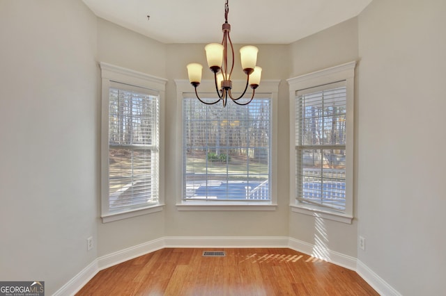 unfurnished dining area featuring hardwood / wood-style flooring and a chandelier