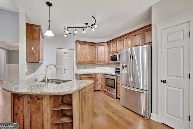 kitchen with sink, light stone counters, hanging light fixtures, appliances with stainless steel finishes, and kitchen peninsula