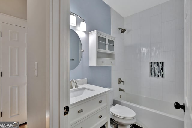 full bathroom featuring tiled shower / bath, vanity, and toilet