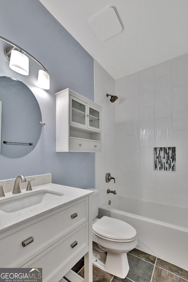 full bathroom featuring tiled shower / bath, vanity, and toilet