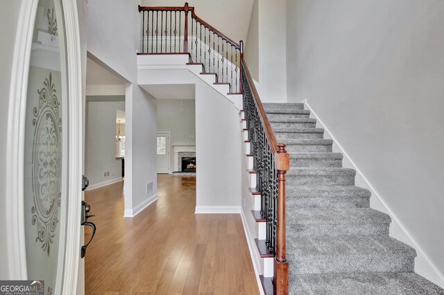 staircase with wood-type flooring and a towering ceiling