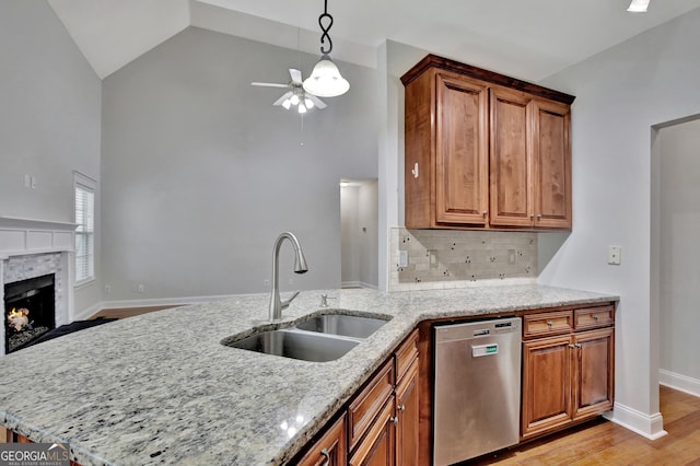 kitchen featuring sink, stainless steel dishwasher, light stone counters, kitchen peninsula, and light wood-type flooring