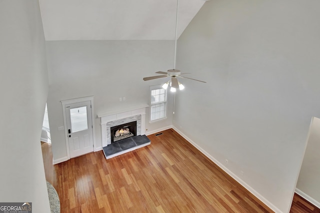 unfurnished living room with light hardwood / wood-style flooring, a fireplace, high vaulted ceiling, and ceiling fan