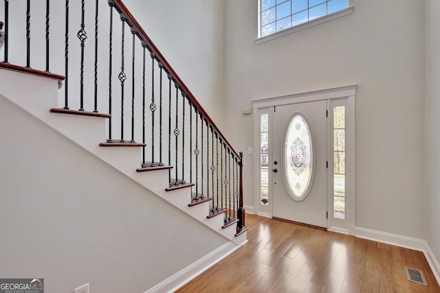 entrance foyer featuring a towering ceiling and light wood-type flooring