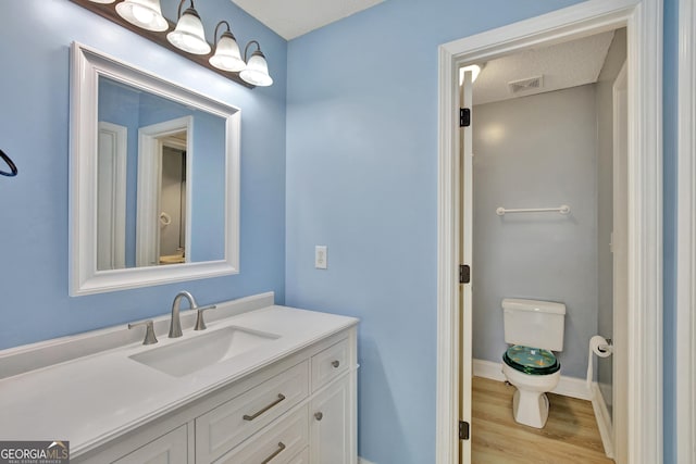 bathroom with wood-type flooring, vanity, and toilet