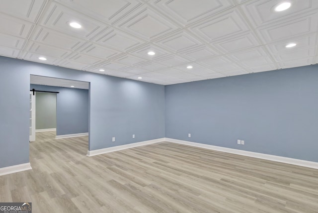 spare room featuring a barn door and light hardwood / wood-style flooring