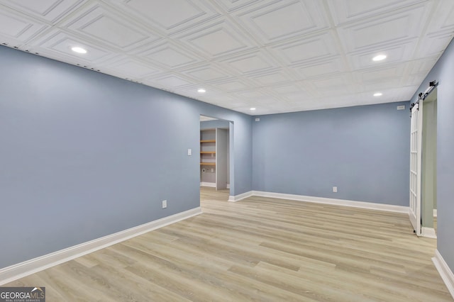 empty room with a barn door and light wood-type flooring