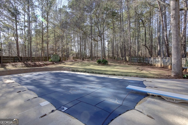 view of pool with a diving board, a yard, and a shed