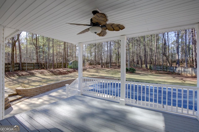 wooden deck featuring a storage shed and ceiling fan