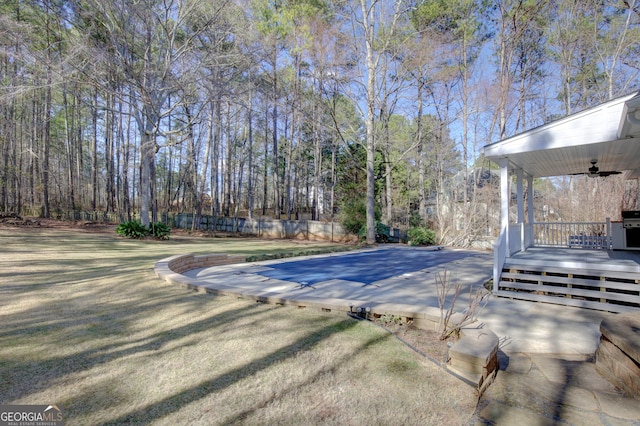 view of swimming pool with ceiling fan, a deck, and a lawn