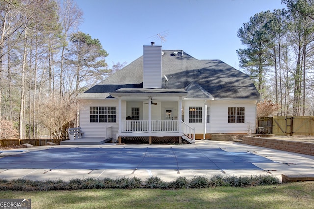 rear view of property with a patio area, a covered pool, and a porch