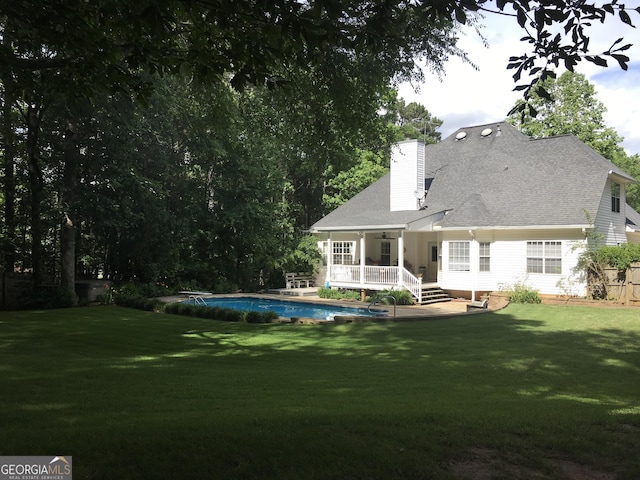 rear view of house with a pool side deck and a yard