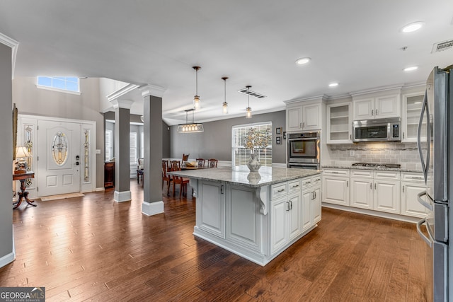 kitchen with white cabinetry, hanging light fixtures, a kitchen island, and appliances with stainless steel finishes