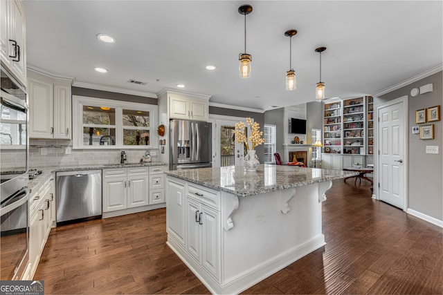 kitchen featuring pendant lighting, sink, appliances with stainless steel finishes, a center island, and white cabinets