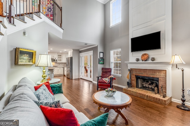 living room featuring a towering ceiling, hardwood / wood-style floors, and a fireplace