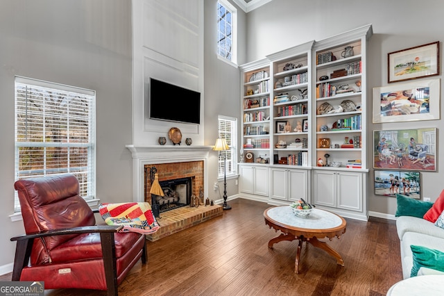 sitting room with dark wood-type flooring, a fireplace, and a high ceiling