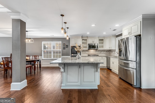 kitchen featuring a kitchen island, appliances with stainless steel finishes, decorative light fixtures, white cabinetry, and light stone countertops