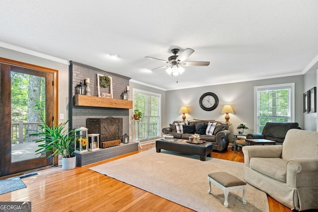 living room with a fireplace, wood-type flooring, ornamental molding, and a healthy amount of sunlight