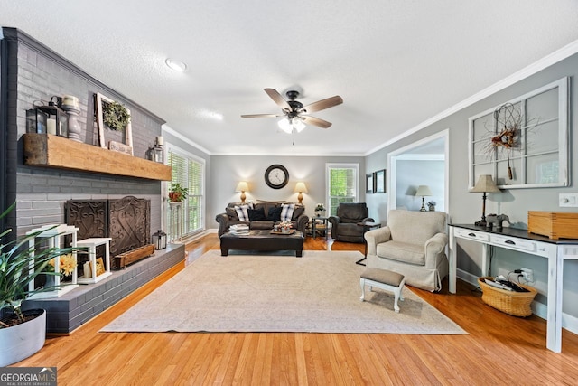 living room with ornamental molding, a brick fireplace, wood-type flooring, and plenty of natural light