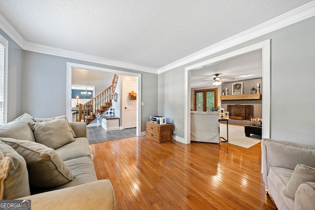 living room with wood-type flooring, ornamental molding, and a textured ceiling