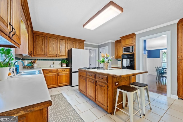 kitchen featuring sink, a breakfast bar area, a center island, stainless steel microwave, and black oven