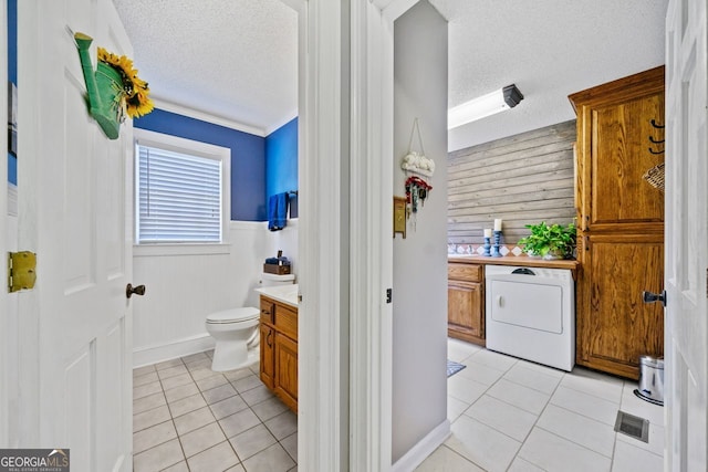 bathroom featuring tile patterned floors, toilet, washer / dryer, and a textured ceiling