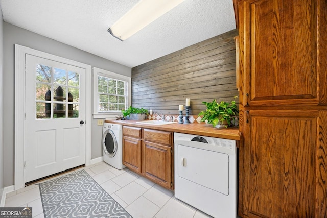 clothes washing area featuring washer / clothes dryer, sink, a textured ceiling, and light tile patterned floors