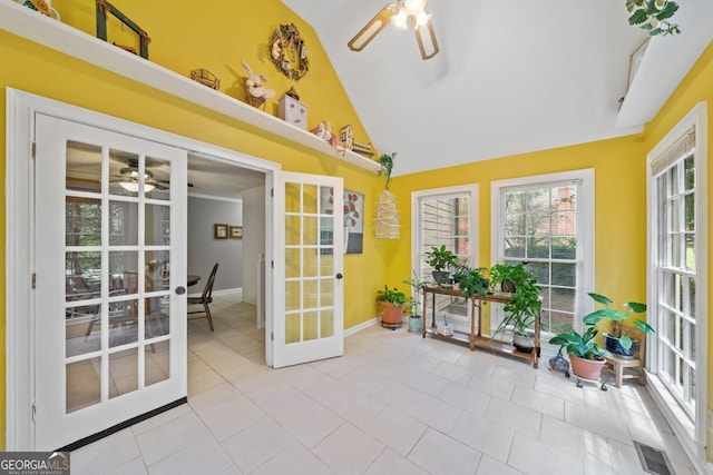 sunroom / solarium with lofted ceiling, ceiling fan, and french doors