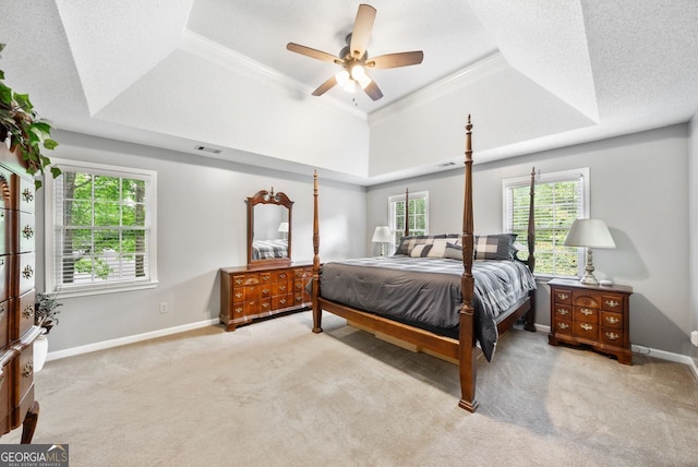 bedroom featuring ceiling fan, light carpet, a textured ceiling, and a tray ceiling