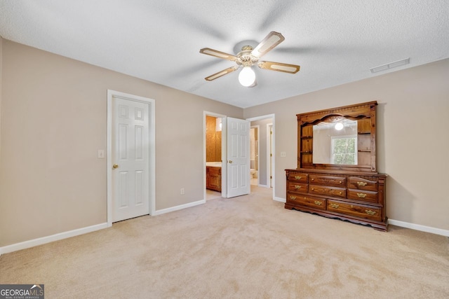 unfurnished bedroom featuring light carpet, ceiling fan, connected bathroom, and a textured ceiling