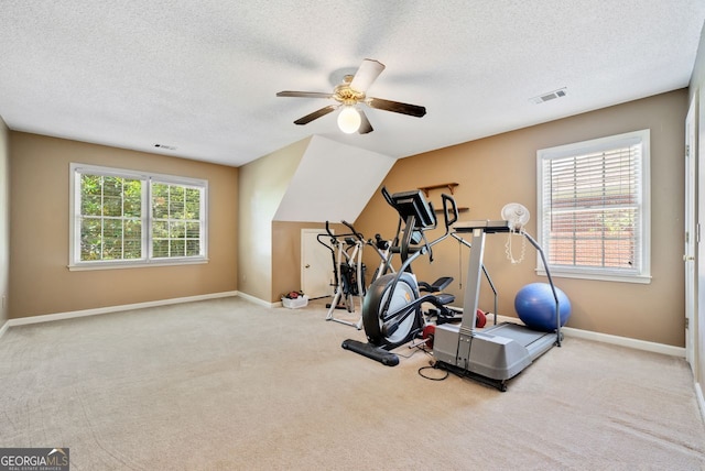 workout area with light colored carpet, a textured ceiling, and ceiling fan