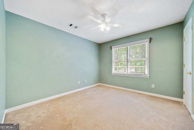 spare room featuring light carpet, ceiling fan, and a textured ceiling