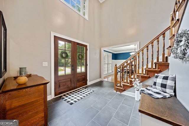 tiled foyer featuring a towering ceiling and french doors