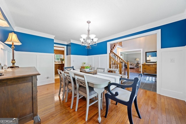 dining room with a notable chandelier, crown molding, hardwood / wood-style floors, and a textured ceiling