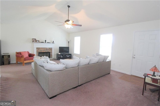 carpeted living room with lofted ceiling, a stone fireplace, and ceiling fan