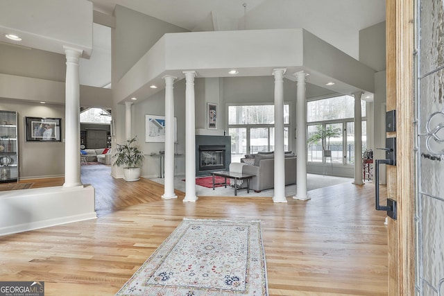 foyer entrance featuring light hardwood / wood-style floors, a high ceiling, and ornate columns