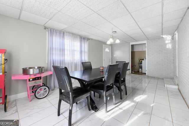 dining space with a paneled ceiling and brick wall