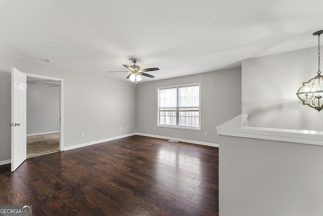 unfurnished room featuring dark hardwood / wood-style flooring and ceiling fan with notable chandelier