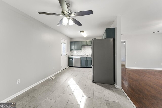 kitchen with sink, gray cabinets, ceiling fan, appliances with stainless steel finishes, and decorative backsplash