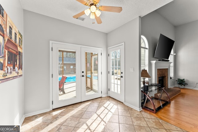 doorway to outside featuring a brick fireplace, plenty of natural light, french doors, and a textured ceiling