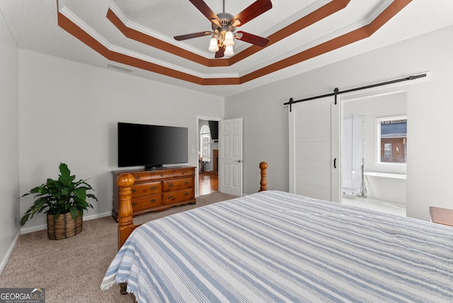 carpeted bedroom with connected bathroom, ornamental molding, a tray ceiling, ceiling fan, and a barn door