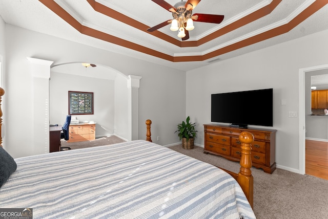 carpeted bedroom with a raised ceiling, ornamental molding, and ceiling fan