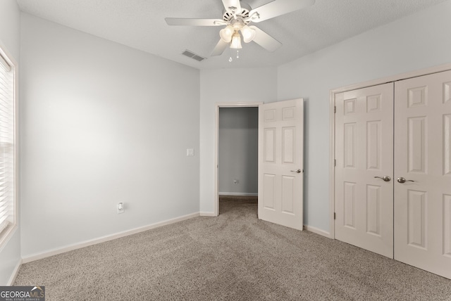 unfurnished bedroom with ceiling fan, a closet, a textured ceiling, and carpet flooring