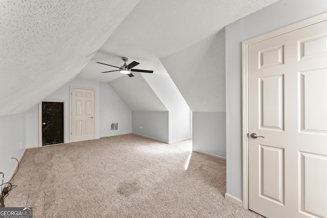 additional living space with lofted ceiling, ceiling fan, light colored carpet, and a textured ceiling