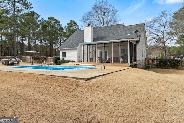 rear view of house with a patio, a fenced in pool, a sunroom, and a lawn