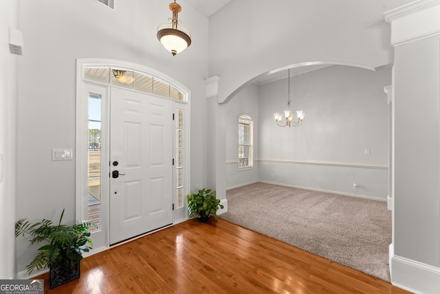 foyer entrance featuring hardwood / wood-style flooring, a towering ceiling, and a chandelier