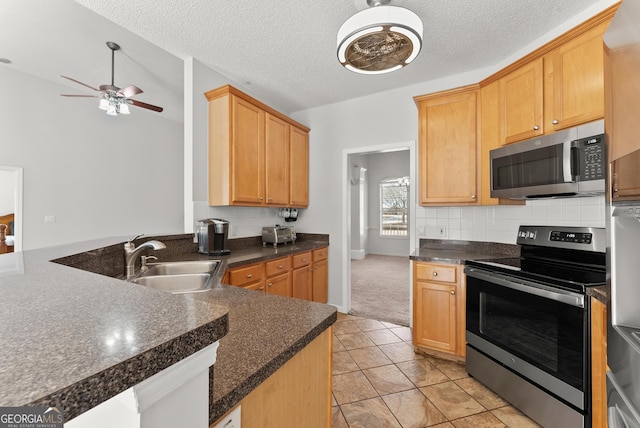 kitchen with tasteful backsplash, sink, kitchen peninsula, stainless steel appliances, and a textured ceiling