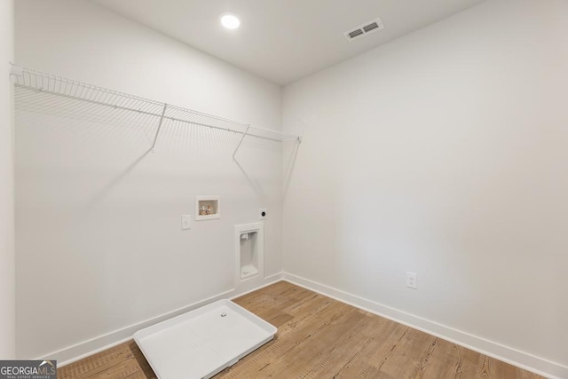 clothes washing area featuring hardwood / wood-style flooring, washer hookup, and hookup for an electric dryer