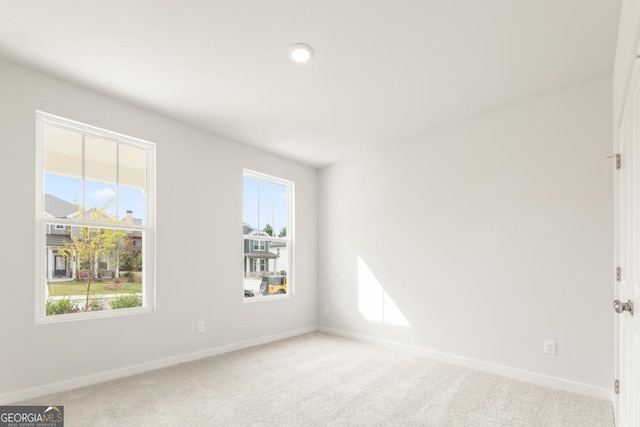 spare room featuring a wealth of natural light and light colored carpet