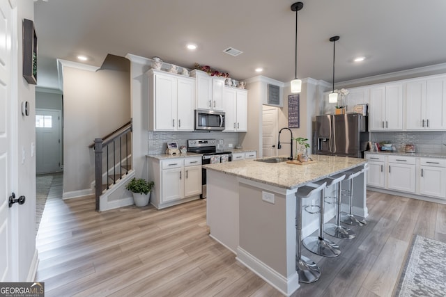 kitchen featuring sink, an island with sink, white cabinets, and appliances with stainless steel finishes